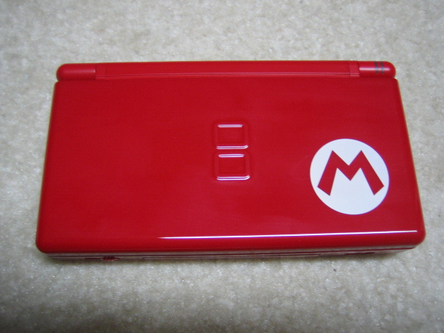 Red Nintendo DS Lite with a Mario symbol on the bottom right